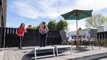 An outdoor deck with a wooden floor, a metal table, and two chairs.