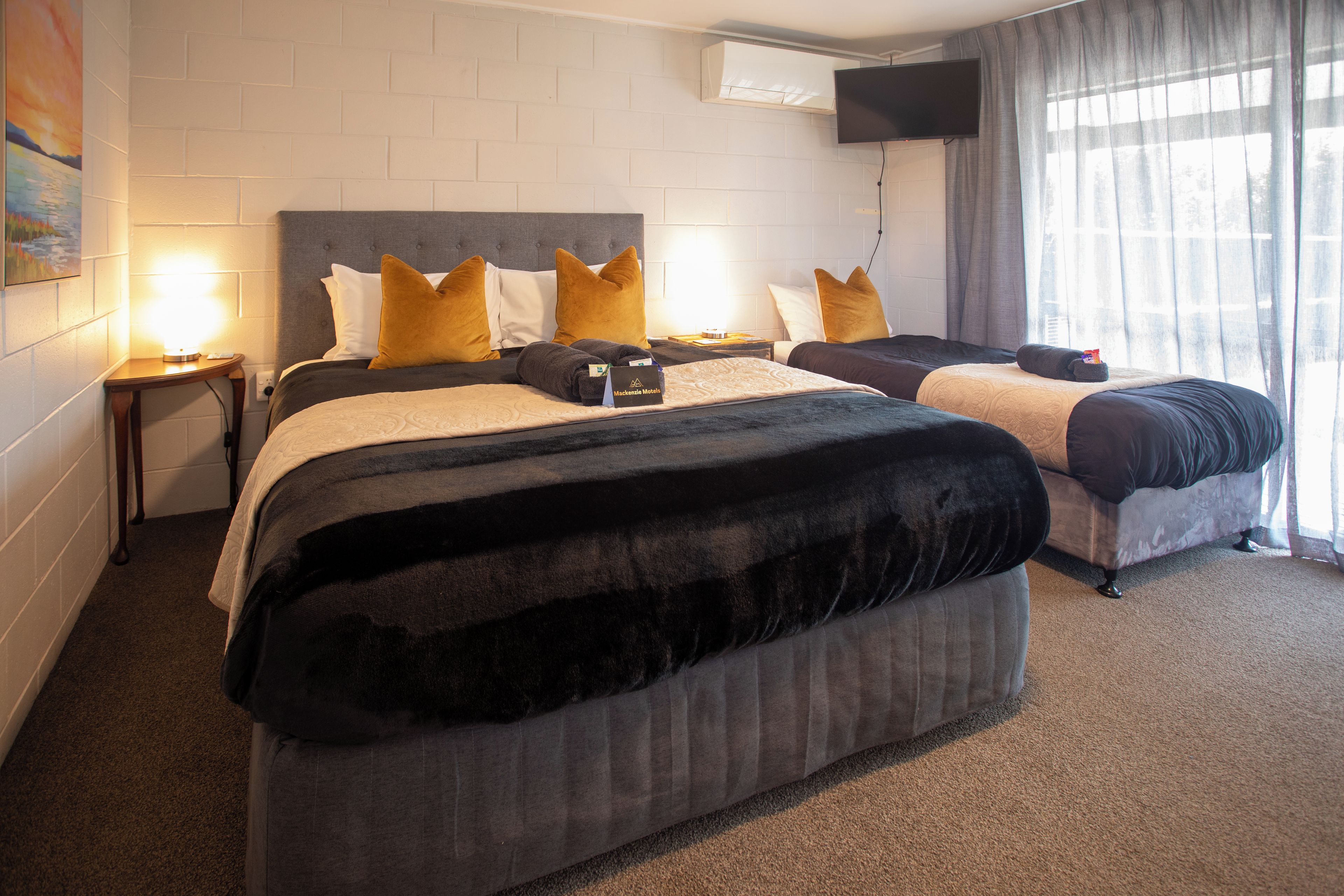 Een hotelkamer met twee bedden, een flatscreen televisie aan de muur en een schilderij.