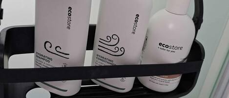 A black metal shelf with three white bottles of skincare products labeled 'ecostore'.