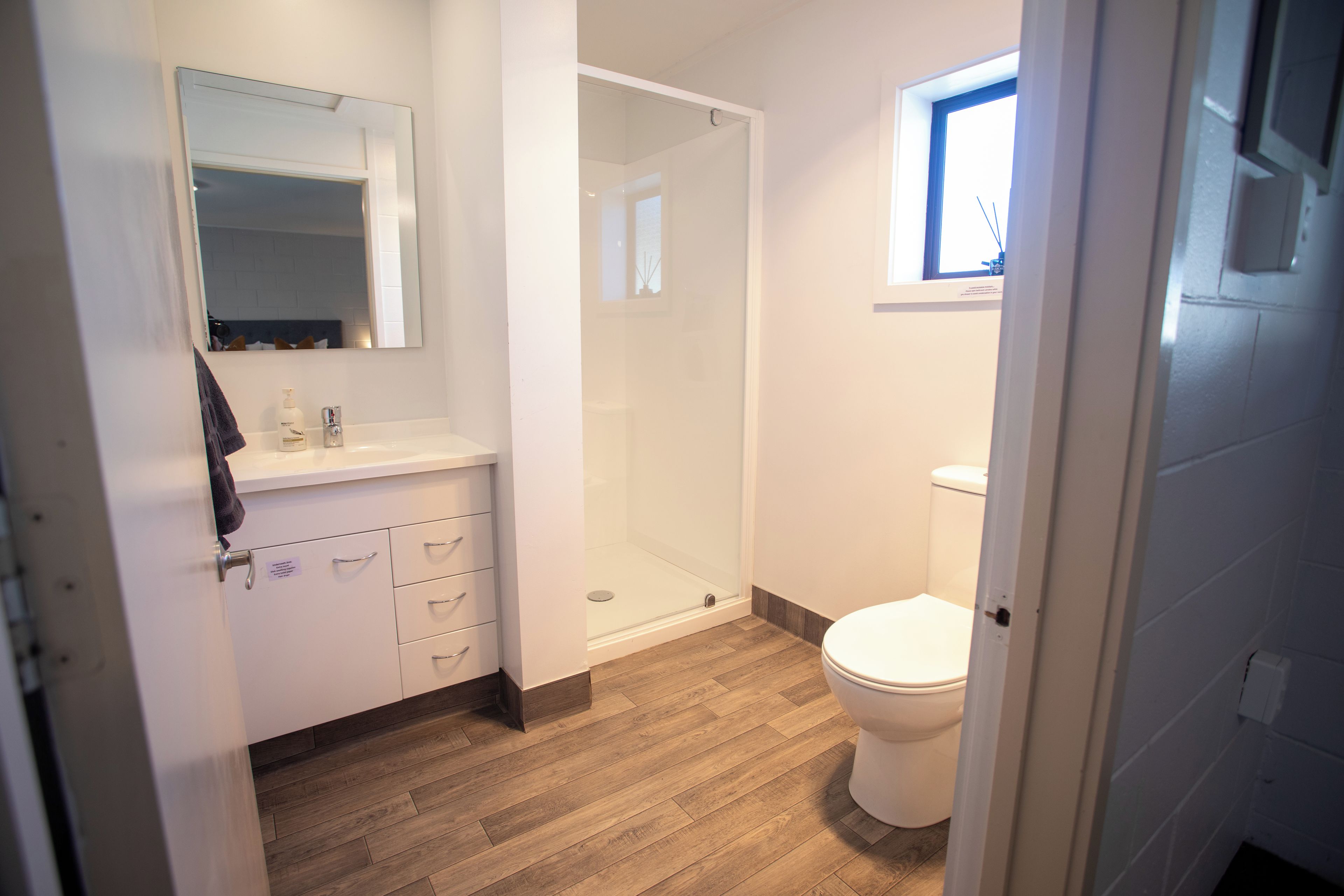 Un bagno con doccia, toilette e specchio sopra il lavandino.