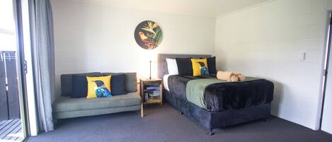 Ein Zimmer mit zwei Betten, einem Sofa, einem kleinen Tisch und einem an der Wand hängenden Bild.