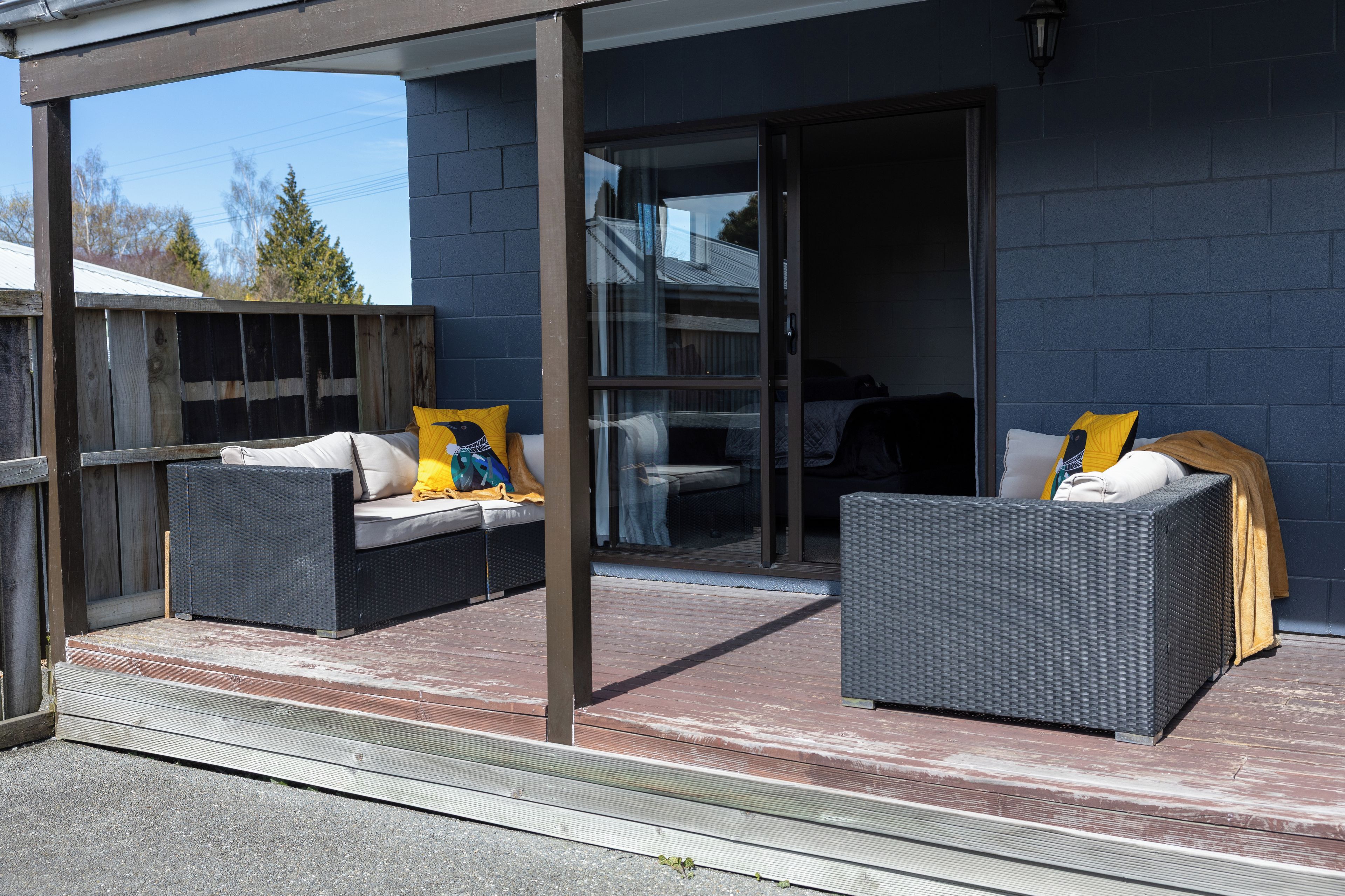 A covered outdoor seating area with wicker furniture and cushions.