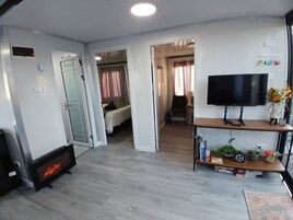A living room with a fireplace, a television on a stand, and a bookshelf.