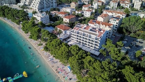 Vista aérea de una zona costera con playa, un gran hotel de varios pisos y edificios residenciales circundantes.