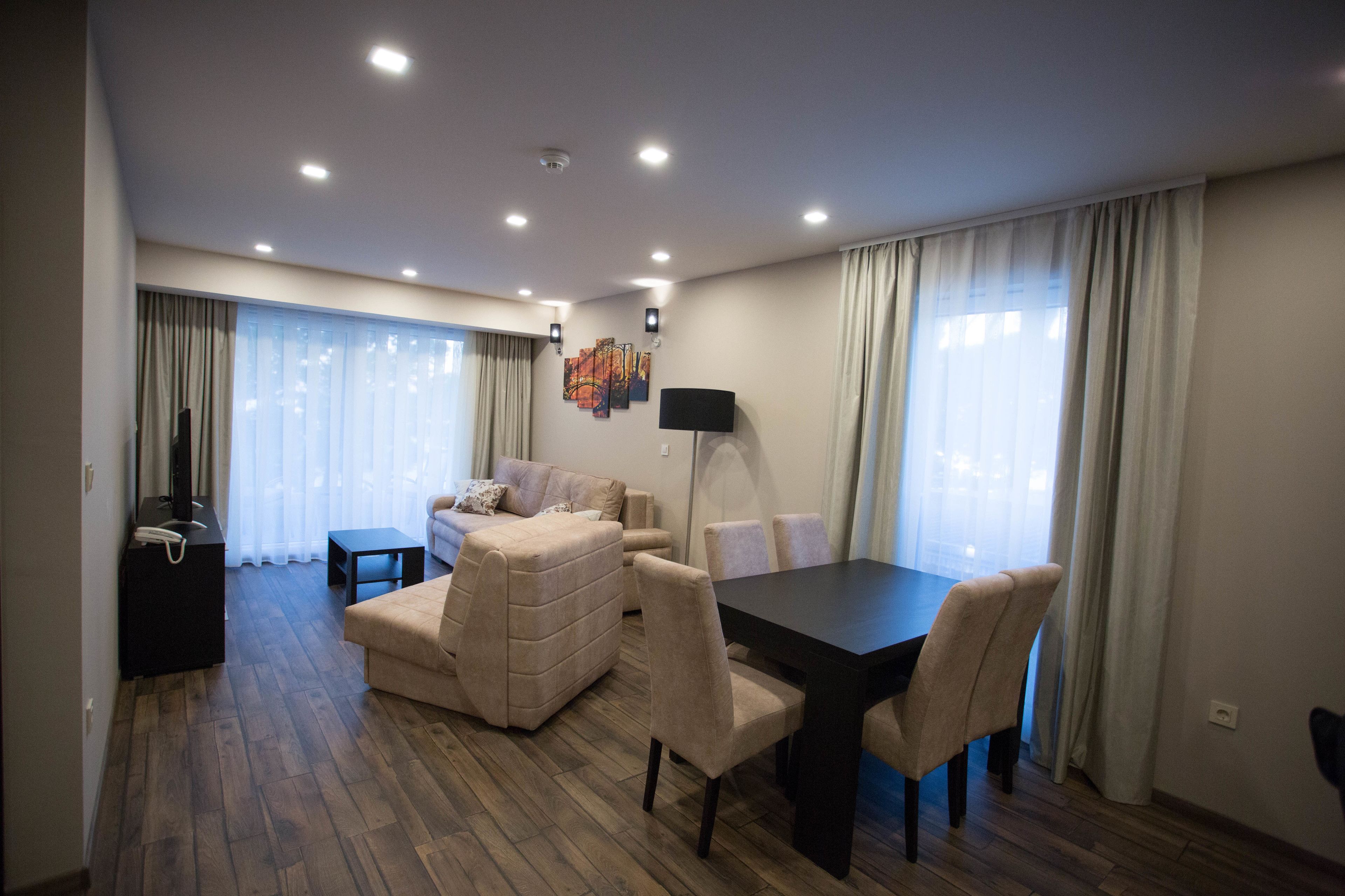 Un salon moderne comprenant un canapé, une table à manger avec des chaises, un téléviseur à écran plat et une lampe.