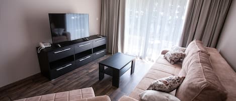 Un salon moderne avec un canapé, une table basse et un téléviseur posé sur un meuble noir.