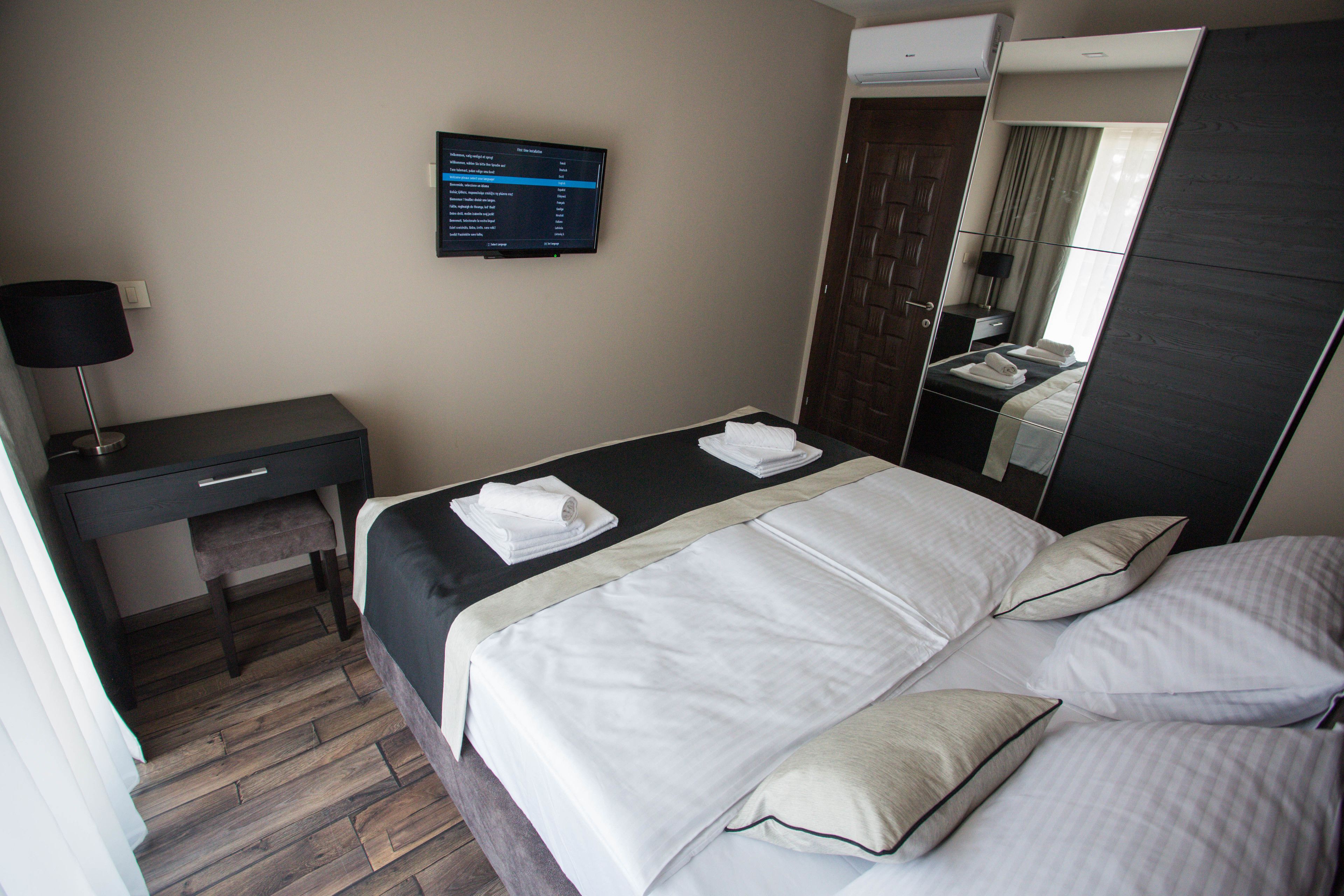 Hotelkamer met een bed, bureau, stoel, flatscreen-televisie en spiegel.