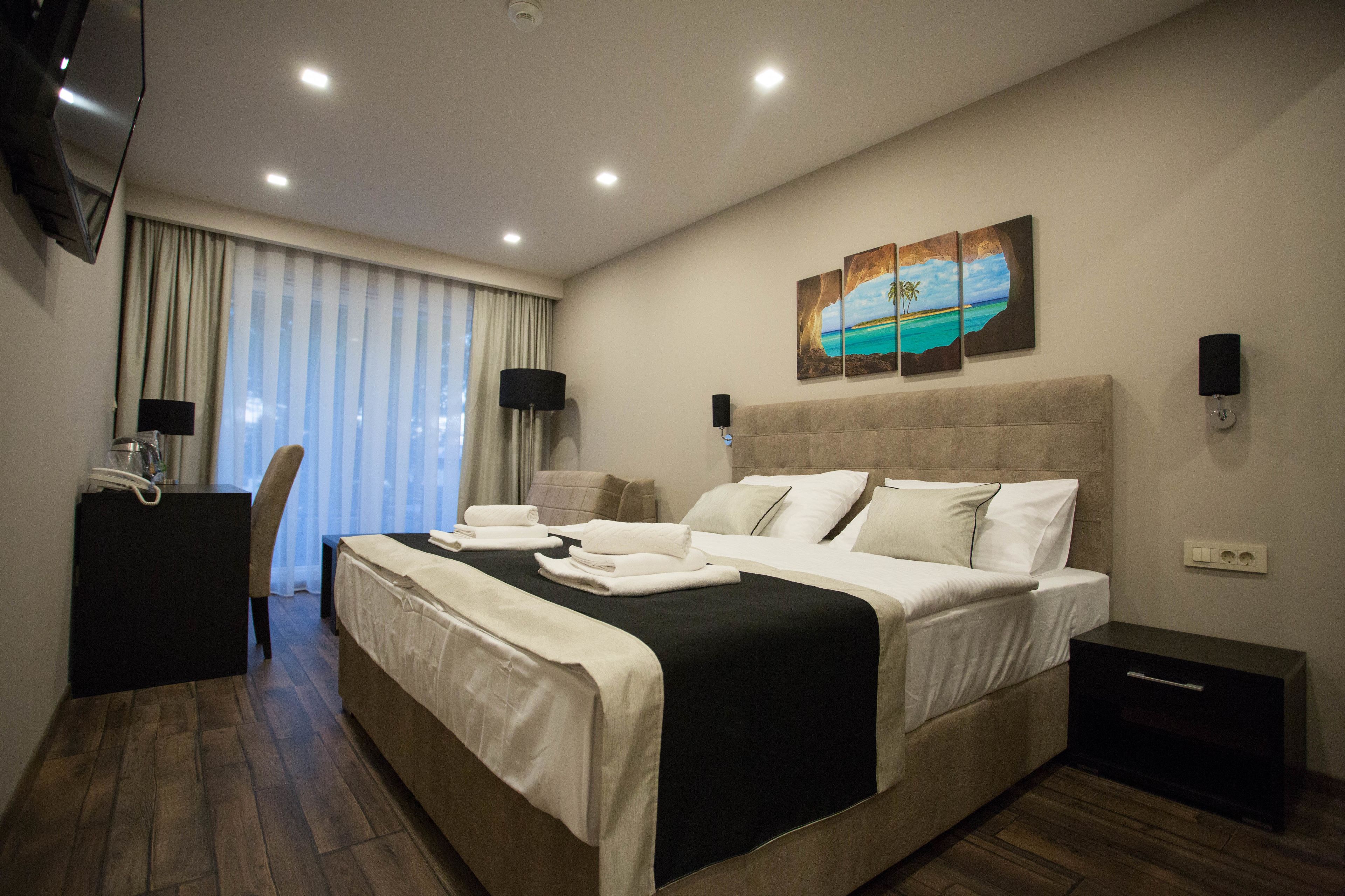 A modern hotel room with a large bed, a desk, and a TV.