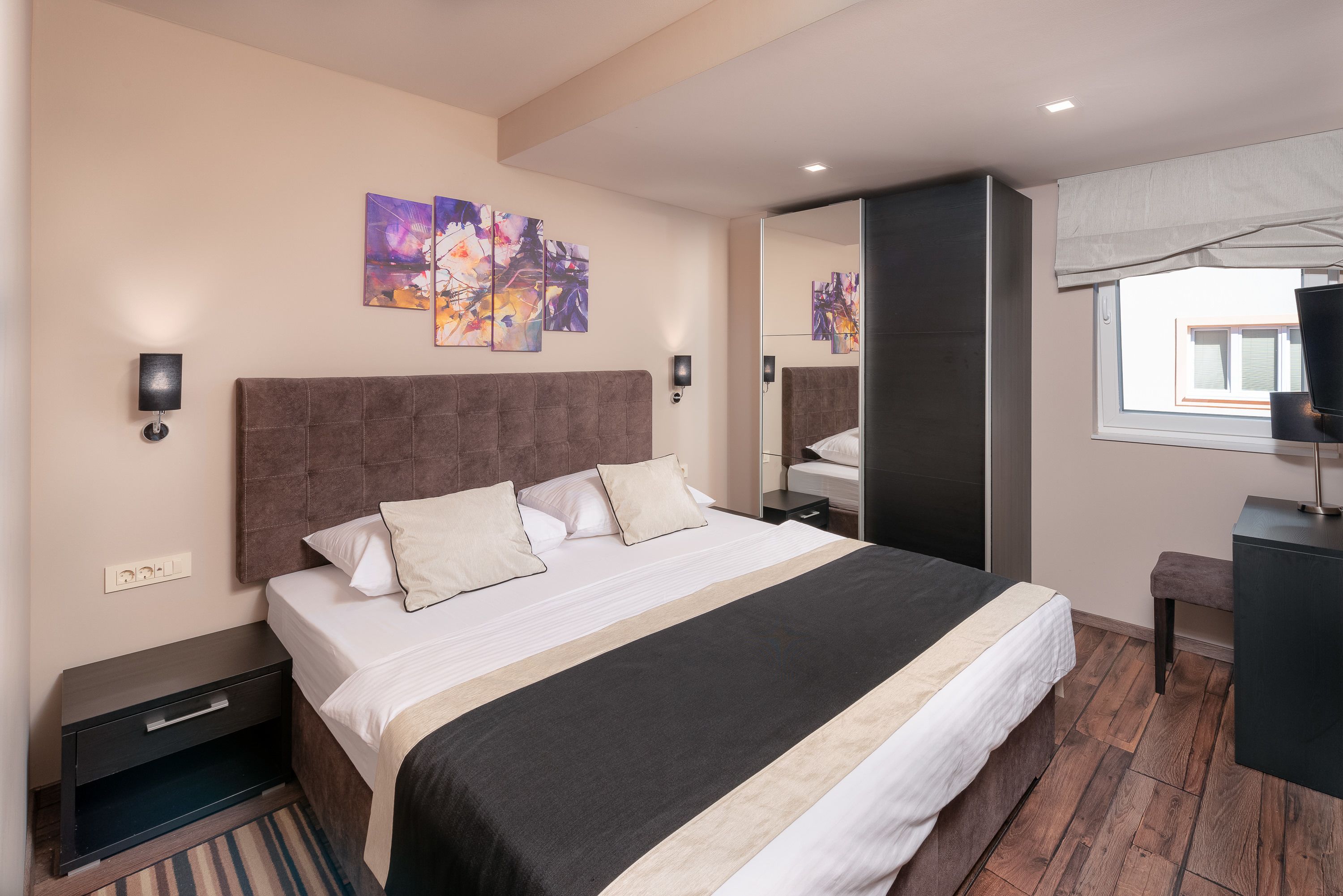 Una habitación de hotel moderna con una cama grande, una mesita de noche, un escritorio y una ventana con vistas.