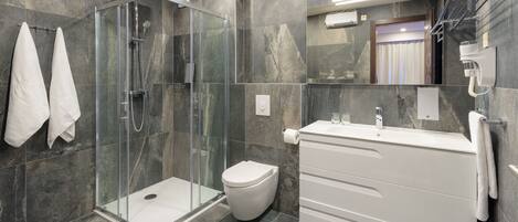 Une salle de bain moderne avec une douche à parois de verre, des toilettes blanches et un meuble-lavabo blanc avec un miroir.