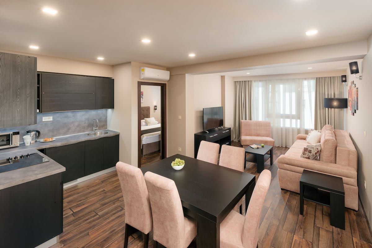 A modern living room with a sofa, a dining table, and a kitchen area with a microwave and sink.