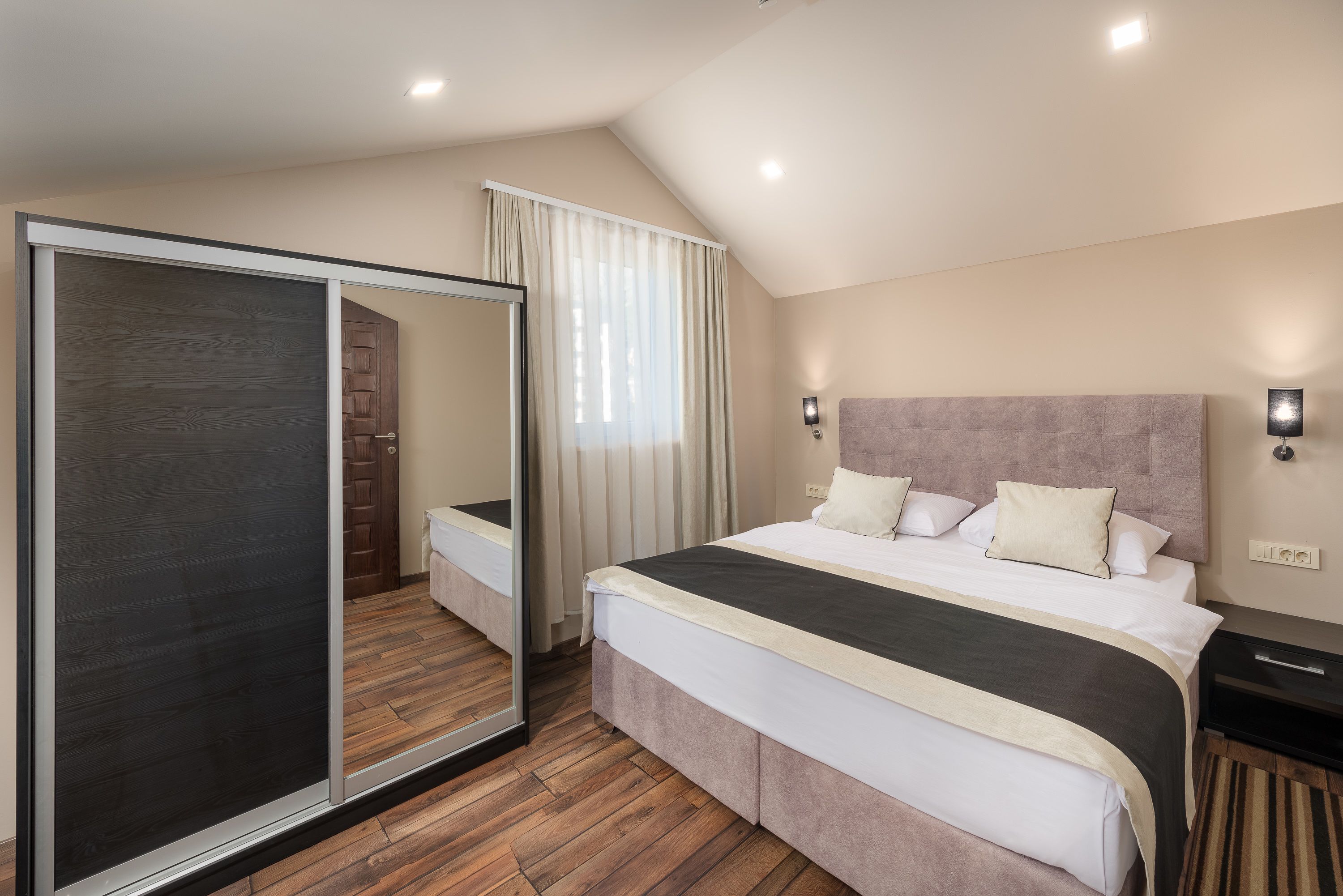 A bedroom with a large bed, a sliding door, and a view of a wooden door and window.