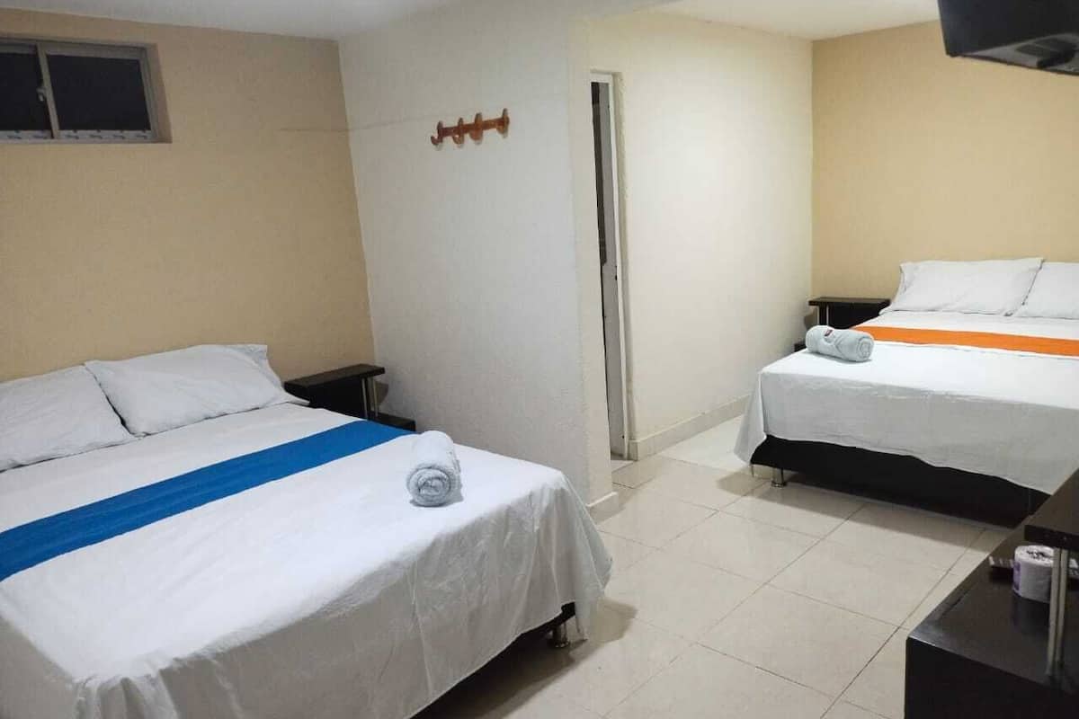 A hotel room with two beds, a small desk, and a TV.