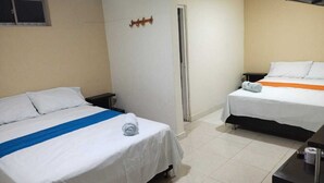 Una habitación de hotel con dos camas, un escritorio pequeño y un televisor.