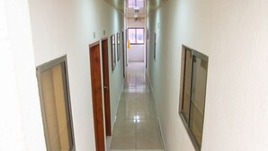 Un pasillo con puertas a ambos lados que conduce a una habitación con un ventanal al final.