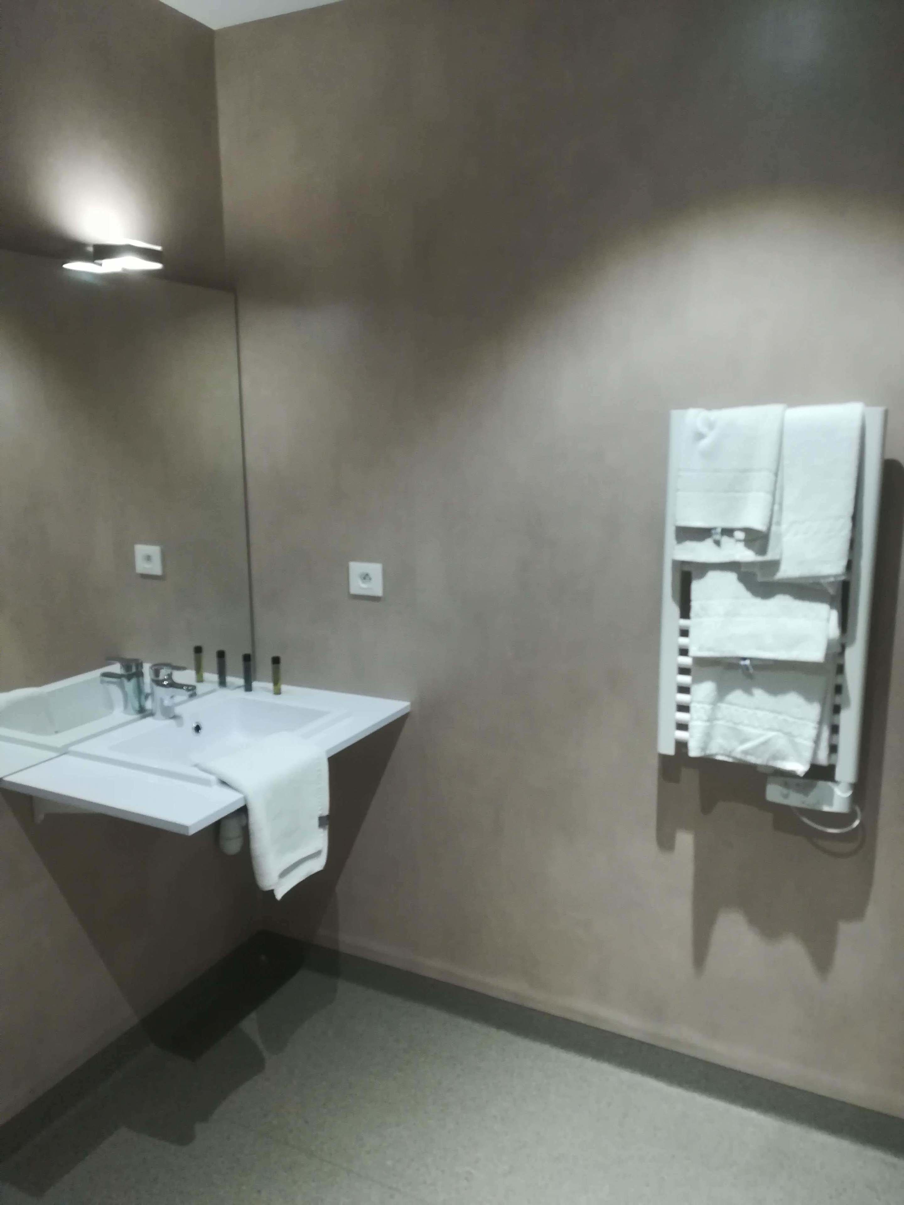 A bathroom with a white sink, a mirror, and a towel rack with multiple towels.
