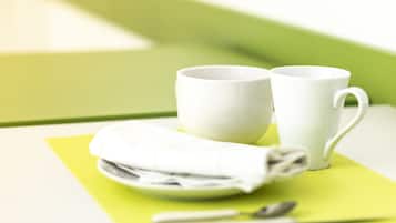 Una mesa con dos tazas blancas, una servilleta doblada y una cuchara sobre un mantel individual verde.