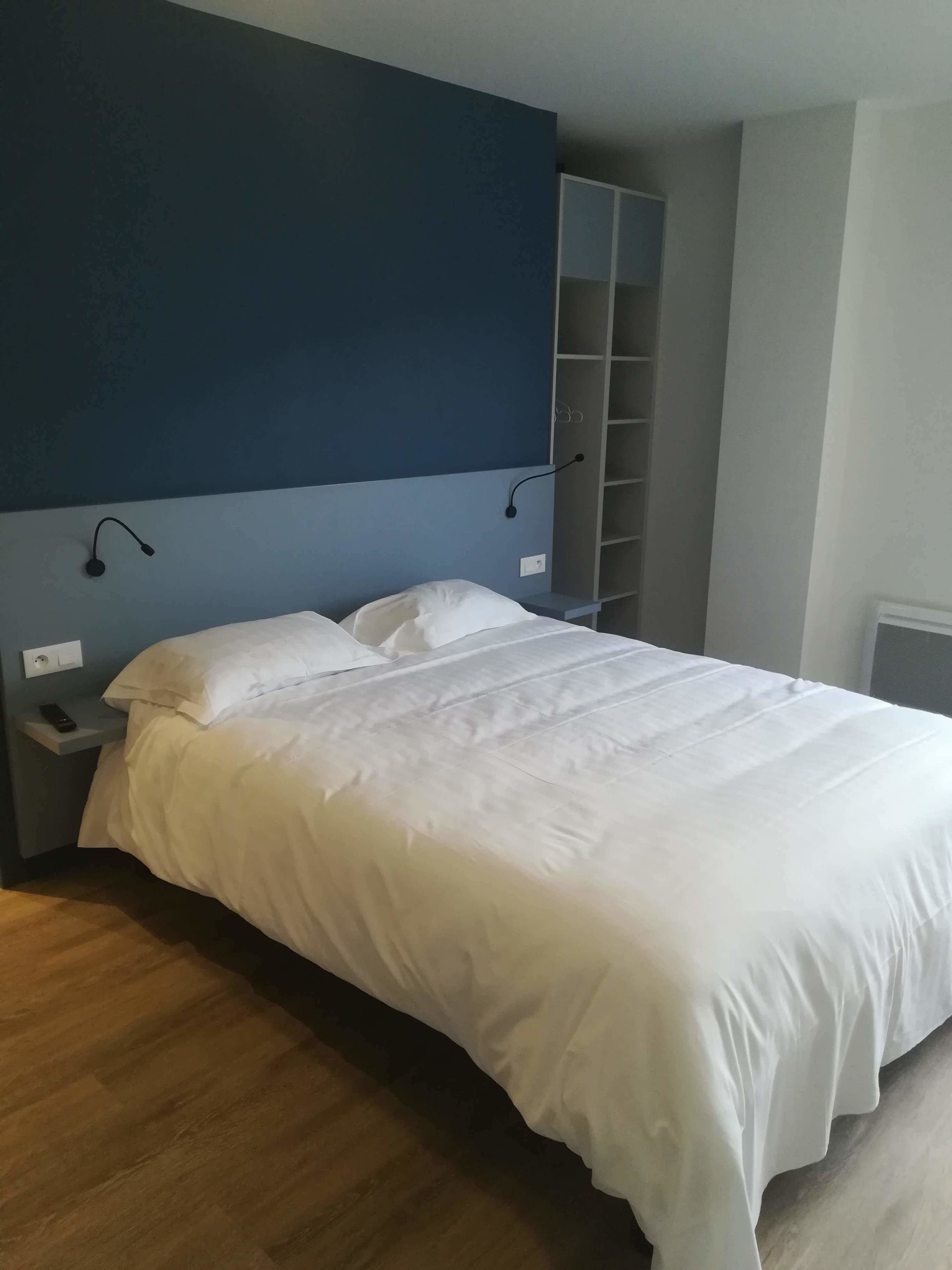 Een slaapkamer met een groot bed, nachtkastje, kledingkast en een ingebouwde boekenkast.