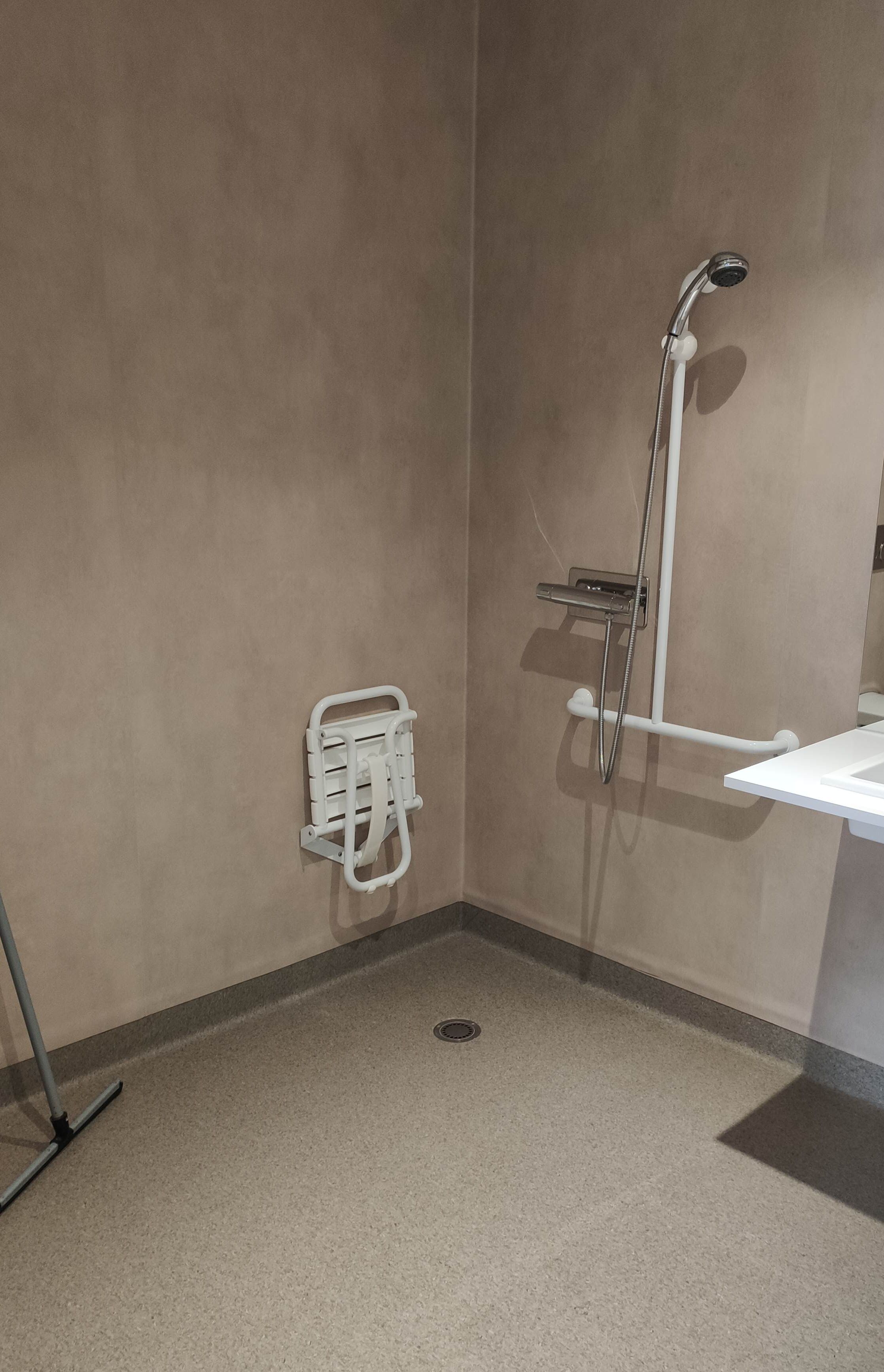 Un baño con ducha, un lavabo blanco y un perchero para toallas.
