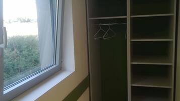 A room with a window, a green and white wardrobe, and a wooden floor.