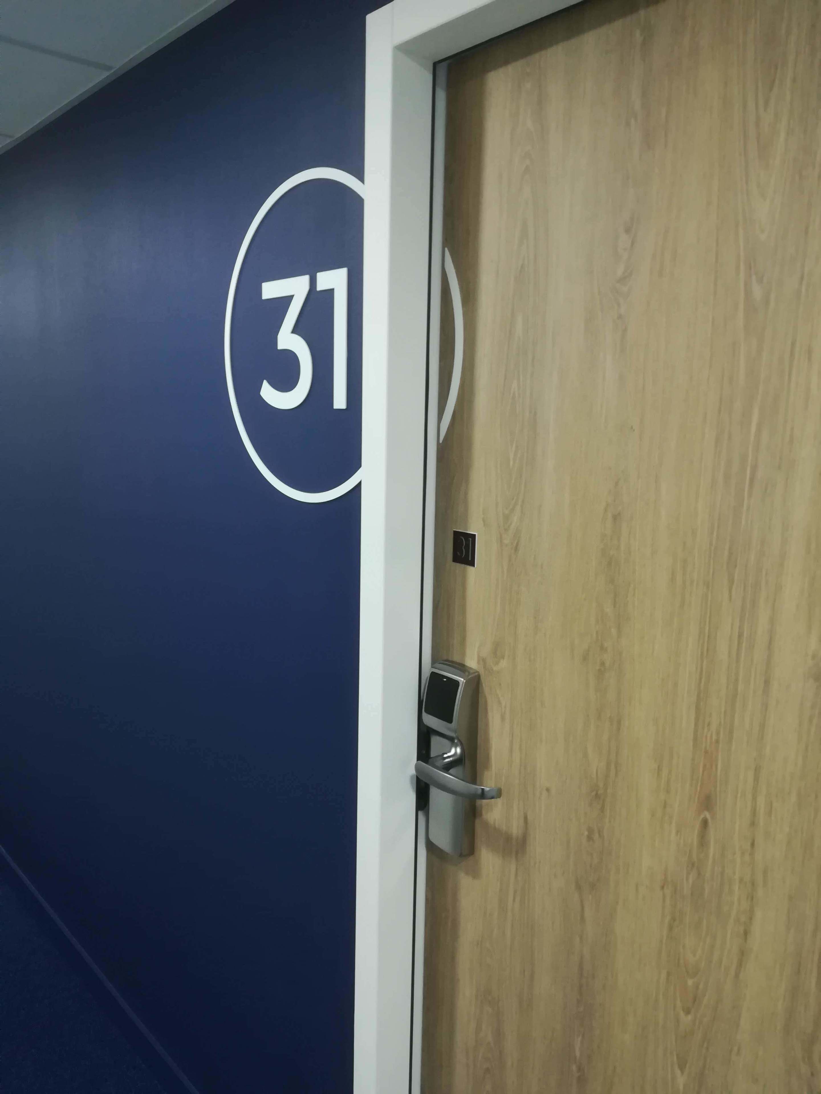 A door with a number 31 sign on the wall, a keypad lock, and a wooden door frame.