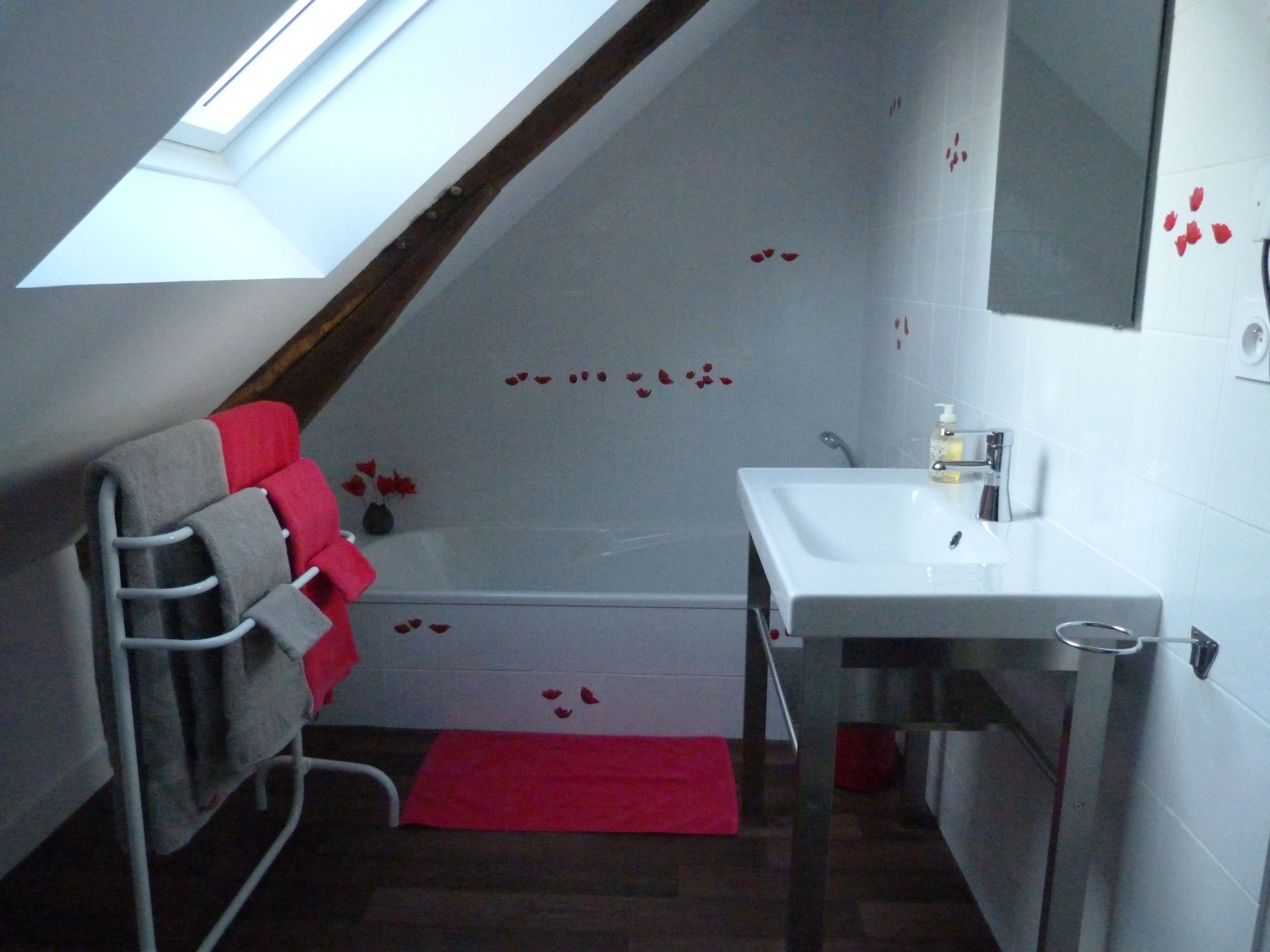 A bathroom with a skylight, a white sink, and a towel rack with towels.