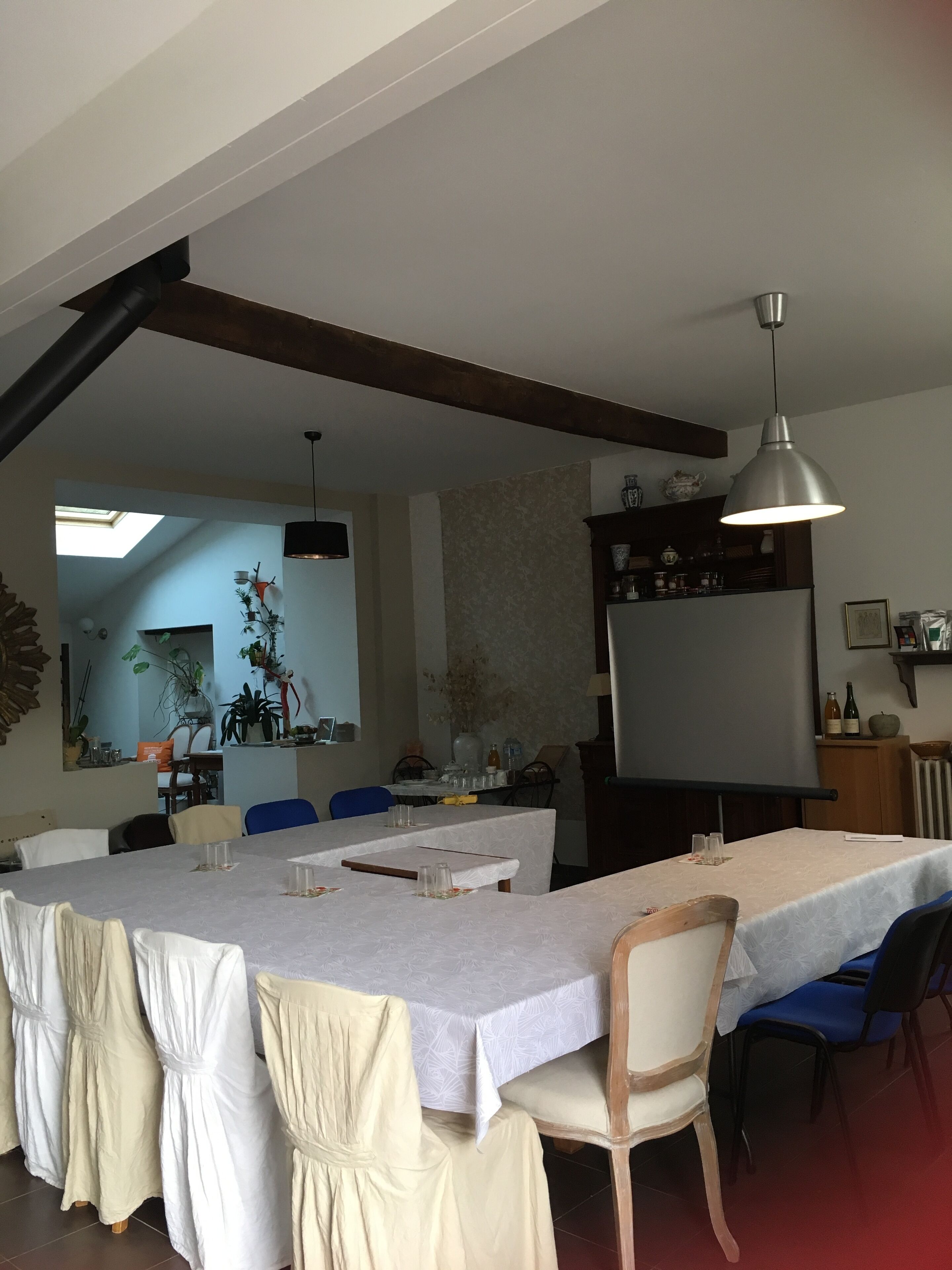 A dining area with a long table, chairs, and a hanging light fixture.