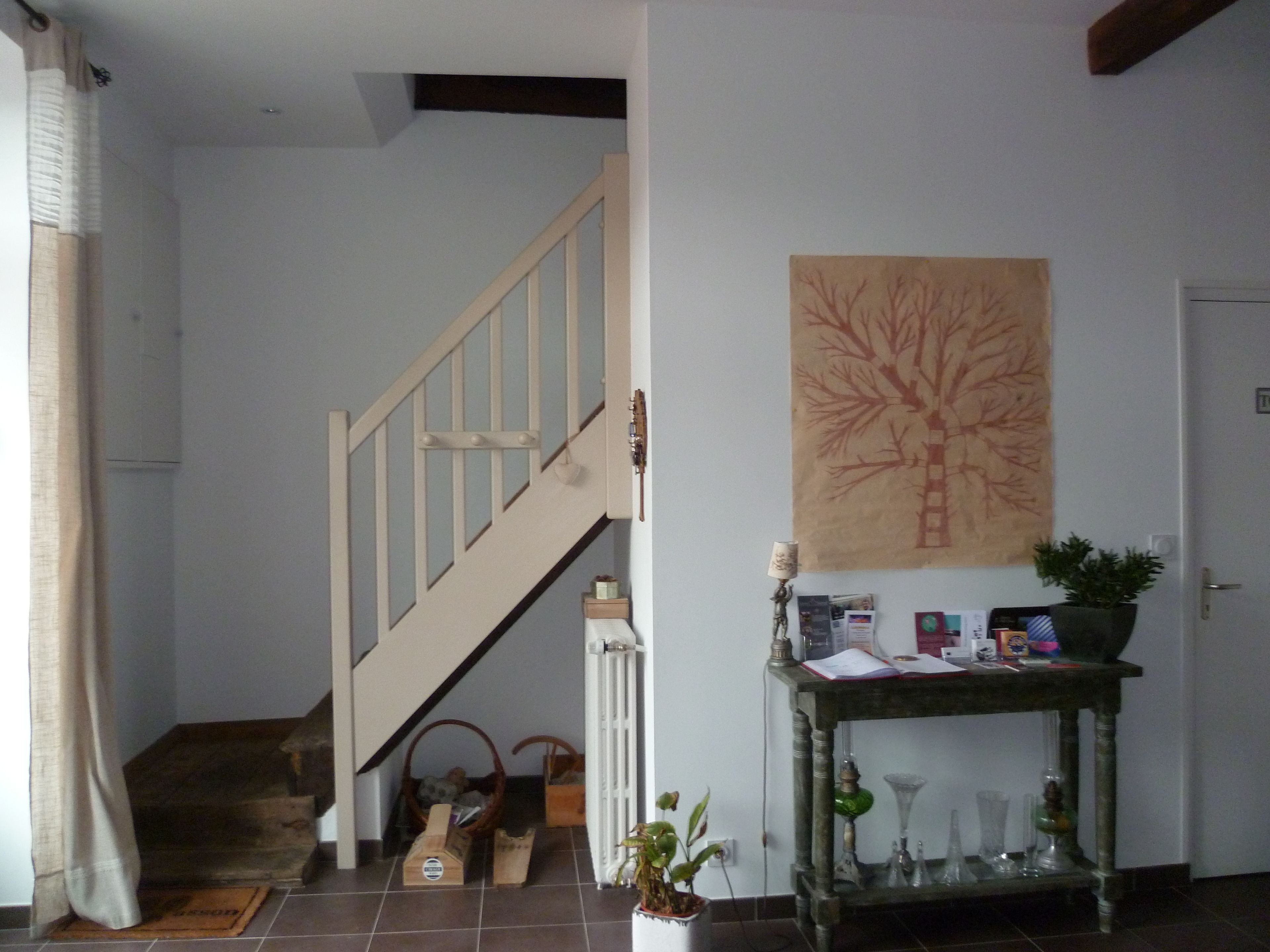 A staircase leading to a second floor, a wall-mounted plant, and a small table with books and a lamp.