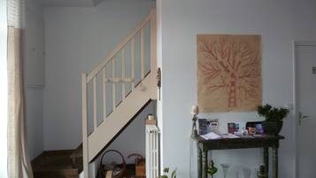 A staircase leading to a second floor, a wall-mounted plant, and a small table with books and a lamp.