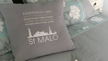 A bed with a pillow featuring a cityscape and text, a starfish, and a seashell.