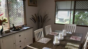 A dining area with a wooden table, white chairs, and a white cabinet. - Egrets Rest - Daintree (Daintree)