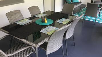 A dining area with a glass-top table, wicker chairs, and a patterned floor.