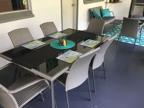 A dining area with a glass-top table, wicker chairs, and a patterned floor. - Egrets Rest - Daintree (Daintree)