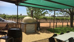 An outdoor seating area with a barbecue grill, a table, and chairs. - The Picker's Hut - Peaceful vineyard setting (Monash)