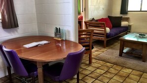 A small, cozy room with a wooden dining table and purple chairs, a sofa with cushions, and a small wooden table. - The Picker's Hut - Peaceful vineyard setting (Monash)