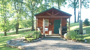 A small wooden cabin with a gravel driveway and a stone pathway leading to the entrance. - 1 Queen size bed &Love seat sofa, Creek view (Shamokin)