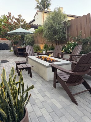 An outdoor patio area with a fire pit, seating, and potted plants.