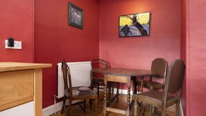 Un coin repas avec une table et des chaises en bois, un radiateur et un tableau encadré au mur.