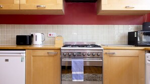 Une cuisine avec des meubles en bois, une cuisinière à gaz, un four à micro-ondes et une machine à café.