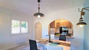 A dining area with a table, chairs, and a kitchen in the background.