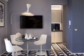 Relax in a stylish room with a round table, mounted TV, and pendant light.