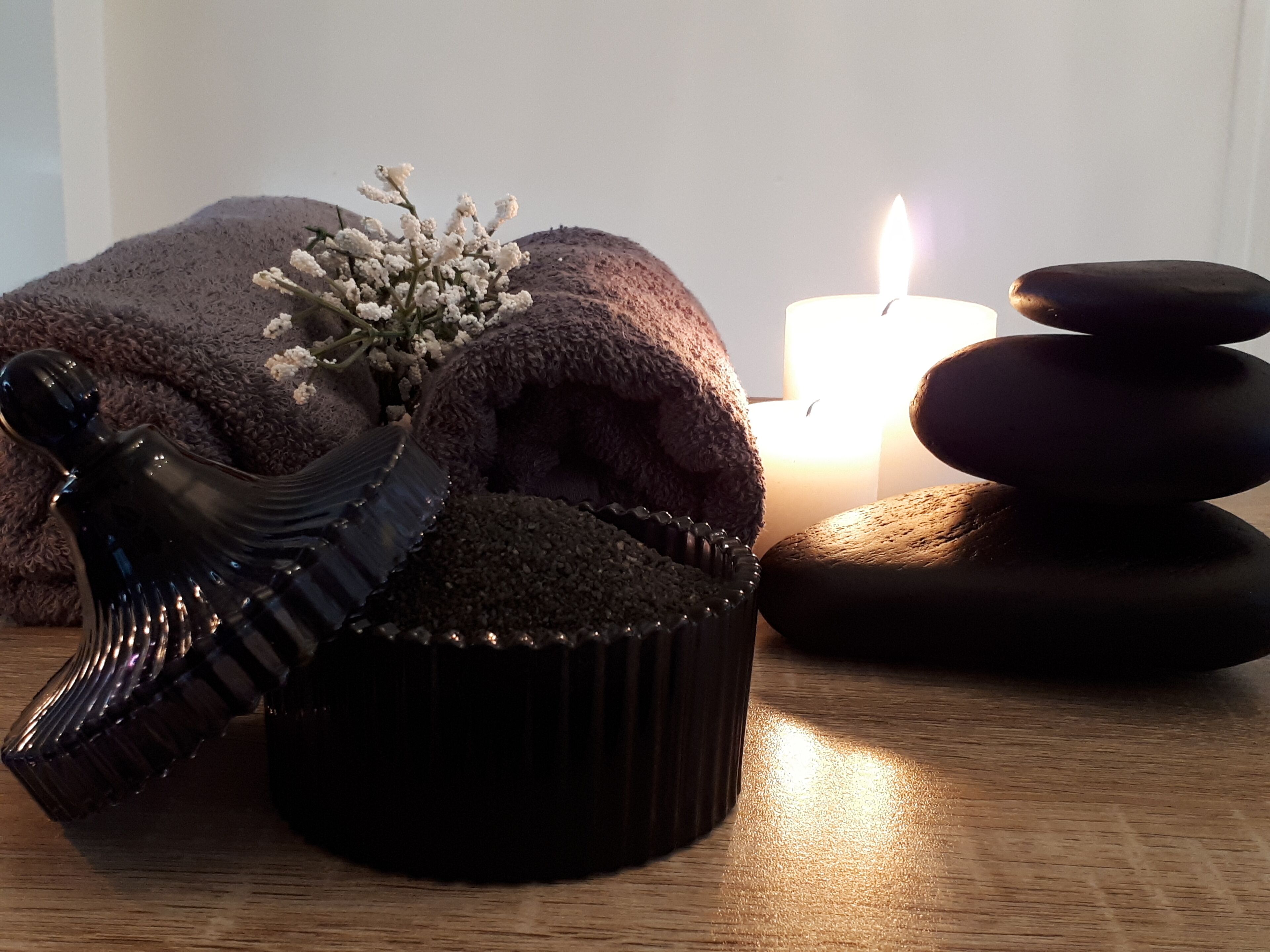 A wooden table with a decorative item, a candle, and a stack of stones.