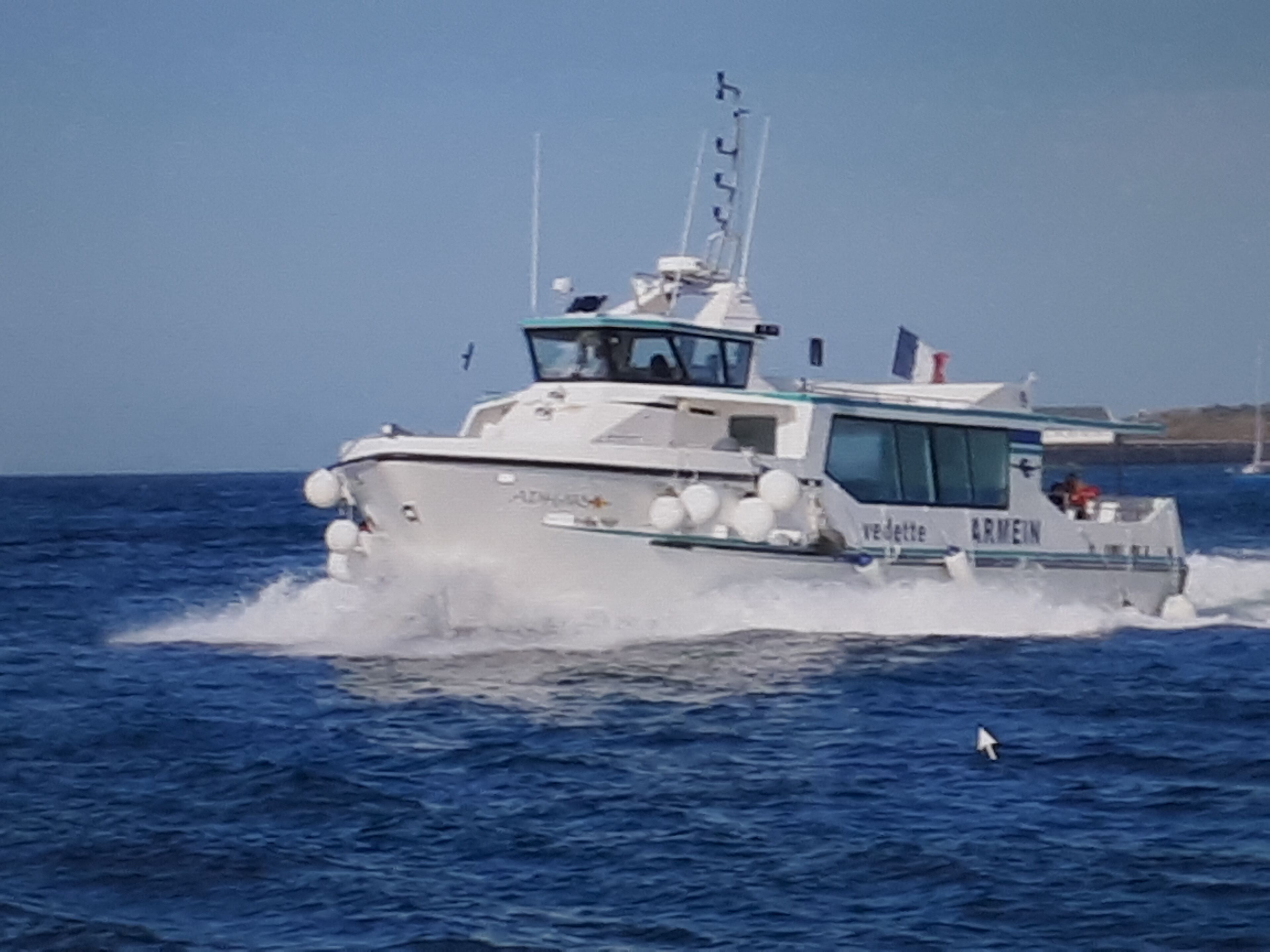 Un bateau portant le nom « ARMEIN » sur sa coque, qui se déplace sur l’eau.