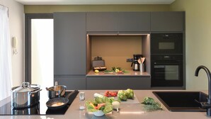 A modern kitchen with a built-in oven, a coffee maker, and a variety of fresh vegetables on the counter. -  Los Lagos 39 Salobre Golf (Maspalomas)