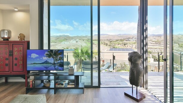 A modern living room with a large sliding glass door leading to a balcony with a scenic view. -  Los Lagos 39 Salobre Golf (Maspalomas)