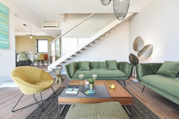 Una sala de estar moderna con un sofá verde, un sillón amarillo y una mesa de centro con libros y vasos.