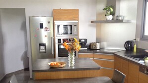 A modern kitchen with a central island, stainless steel appliances, and a dining area with two chairs.