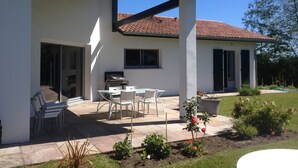 A modern house with a patio, outdoor seating, and a garden.