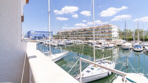 Ein Yachthafen mit mehreren vertäuten Booten, im Hintergrund ein Gebäude mit Balkonen und ein klarer Himmel.