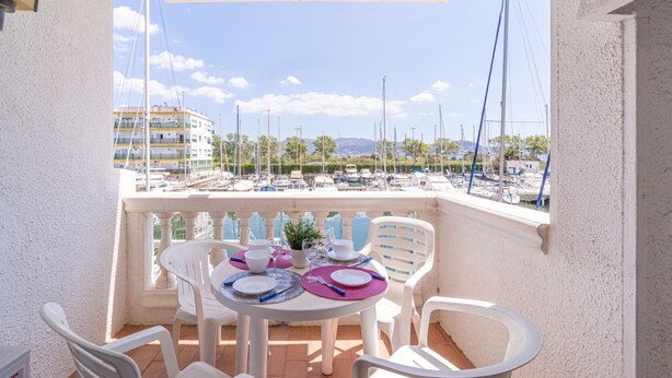Ein Balkon mit Tisch für vier Personen mit Blick auf eine Marina, in der Boote und Gebäude zu sehen sind.